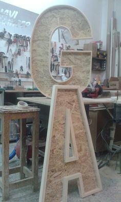 the letter g is made out of plywood, and sits in front of a workbench