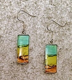 These long dangles have a wonderful  layered abstract effect and would be a great addition to anyone's favorite outfit. The colors are created from very vibrant inks and set in surgical steel.They are finished with a double thick layer of resin which makes them durable and really pops out the rich colors.They are non tarnish and hypoallergenic. Included is a description card and a gold satin gift poach. Artistic Multicolor Hypoallergenic Jewelry, Artistic Multicolor Summer Jewelry, Artistic Drop Earrings For Summer, Nickel-free Multicolor Rectangular Earrings, Multicolor Rectangular Jewelry For Summer, Artsy Dangle Jewelry With Artistic Design, Abstract Design Drop Earrings As Gift, Artistic Multicolor Jewelry With Abstract Design, Artistic Multicolor Abstract Jewelry