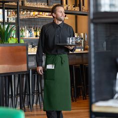 This Choice hunter green standard bistro apron with 1 pocket features a standard length that hits below the knee to protect against spills and stains. This Choice bistro apron is perfect for busy establishments looking for a long uniform that offers ample fabric, versatility, convenience, and ease. Made of a strong poly-cotton blend, this comfortable apron is durable enough to withstand daily wear and tear. Its construction even protects against pilling and shrinkage to maintain your staff's pro Restaurant Uniforms Trendy, Waitstaff Uniform, Cafe Uniform, Bistro Apron, Waiter Uniform, Restaurant Aprons, Green Apron, Restaurant Uniforms, Staff Uniforms