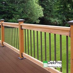 a wooden deck with metal railings in front of green grass and trees on the other side