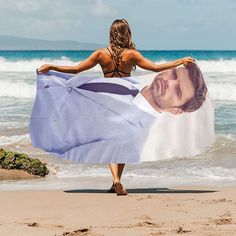 a woman walking on the beach with a towel over her head and an image of a man's face