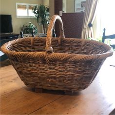 a large wicker basket sitting on top of a wooden table next to a window