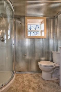 a bathroom with corrugated walls and a toilet in the corner, along with a walk in shower