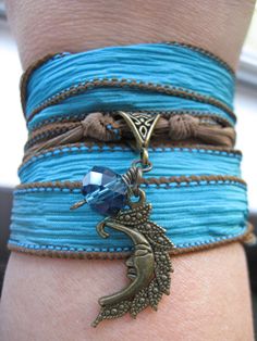 These beautiful blue and brown silk wraps are accented with a bronze-toned moon charm and wrapped faceted aqua glass bead or a silver peacock and teal glass bead. Can be worn as a bracelet--wrap around wrist and tie or tuck ends--or as a necklace. Blue Spiritual Wrap Bracelet For Festival, Blue Bohemian Wrap Bracelet For Festivals, Blue Hand Wrapped Wrap Bracelet For Festivals, Blue Bohemian Handmade Wrap Bracelet, Handmade Blue Wrap Bracelet For Festival, Silk Wrap Bracelets, Teal Glass, Green Beaded Bracelets, Aqua Glass