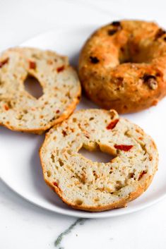 three bagels on a white plate sitting on a table