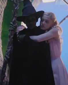 a woman in a witch costume hugging a man wearing a black hat and cloak on the set of harry potter