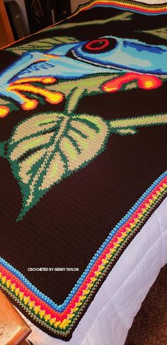 a crocheted blanket on top of a bed in a room with carpeting