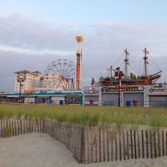 an amusement park with ferris wheel in the background and sand dunes on the beach near by