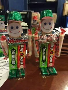 three small candy figures made to look like people with hats and green tinsels on their heads