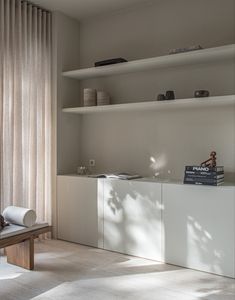 a living room filled with furniture and books on top of white shelving unit units