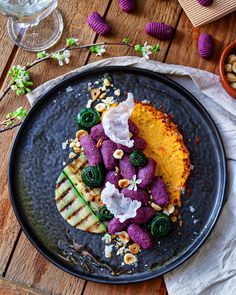 a black plate topped with food on top of a wooden table