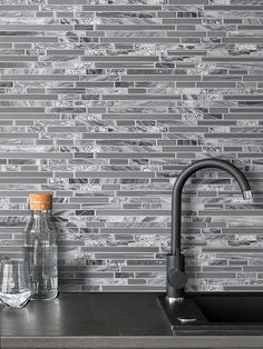 a kitchen sink and faucet in front of a gray tile backsplash