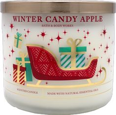 a white candle with red, green and gold wrapped presents on it that says winter candy apple