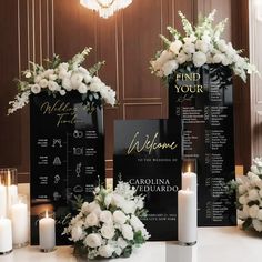 a table topped with white flowers next to candles and menus covered in black paper