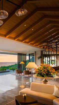 a living room filled with lots of furniture next to a large open area covered in plants