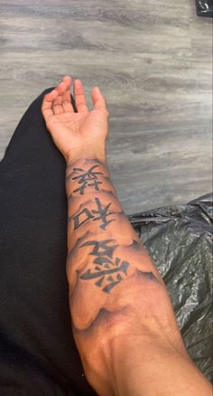 a man's arm with chinese writing on it and his hand in the air