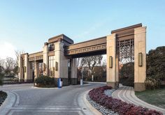 an entrance to a large building with a gate and flowers in the foreground on a sunny day