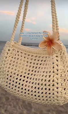 a crocheted purse with a flower on the front hanging from it's side