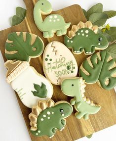 cookies decorated with green and white icing sitting on a cutting board next to leaves