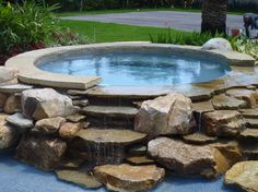 an outdoor pool with rocks and water features