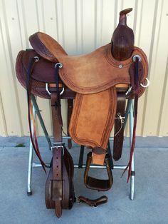 a saddle and reins are sitting in front of a wall