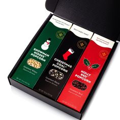 four different types of christmas chocolates in a black box on a white table top