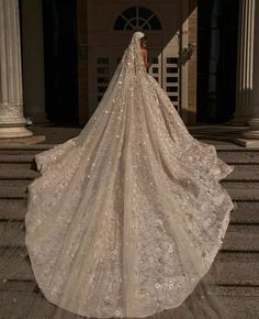 a woman in a wedding dress standing on steps with her back turned to the camera