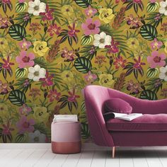 a pink chair sitting in front of a yellow wallpaper with flowers and leaves on it