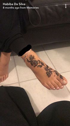 a woman's foot with a flower tattoo on her left leg and black pants