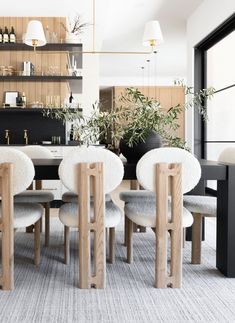 a dining room table with chairs and plants on the shelves in front of it,