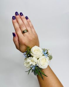 a woman's hand with purple and white nail polish holding a bouquet of flowers