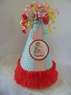 a birthday party hat with red and yellow streamers on the top, sitting on a doily