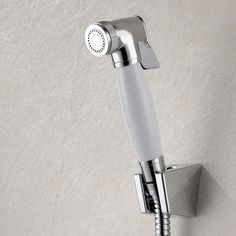 a shower faucet mounted to the side of a wall with a hand held showerhead