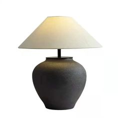 a black table lamp with a white shade on the base and a light in the middle