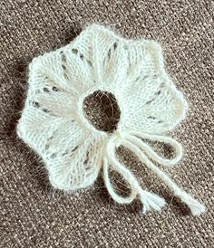 a white crocheted flower on top of a carpeted floor next to a pair of scissors