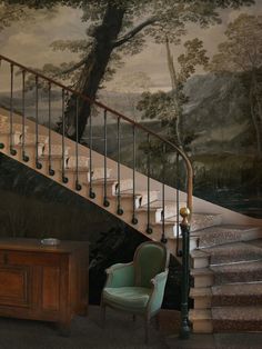 a staircase leading up to a painting on the wall next to a desk and chair