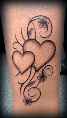 two hearts with vines and flowers on the side of a woman's leg,