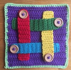 a crocheted square with buttons on the front and sides, made to look like a toy plane