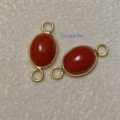 two gold plated pendants with red cabochons on white paper toweling