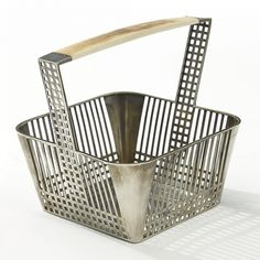 a metal basket with a wooden handle sitting on top of a white table next to it