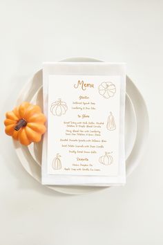 a white plate topped with a menu next to a small pumpkin