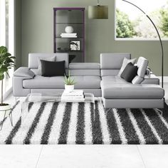 a modern living room with grey couches and black and white rugs on the floor