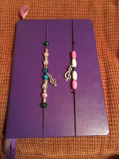 a purple book sitting on top of a couch next to a pair of beaded bracelets