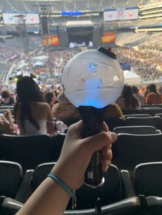 a hand holding a light bulb in front of an arena filled with people at a sporting event