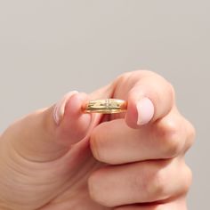 a woman's hand holding a tiny gold ring