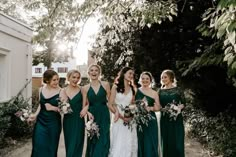 a group of women standing next to each other in front of some trees and bushes