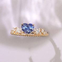 two gold rings with a blue heart shaped sapphire and three white diamonds on each band