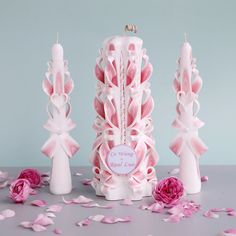 three pink candles are on the table with rose petals around them and one candle has been made out of fondant