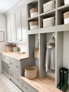 a white kitchen with gray cabinets and baskets on the shelves, along with green rubber boots