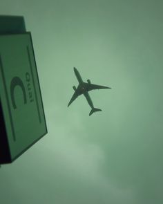 an airplane is flying in the sky near a sign